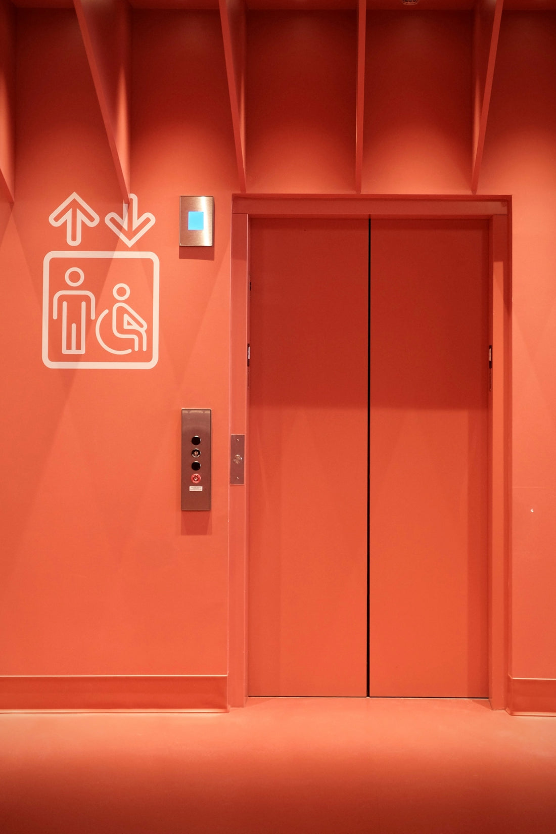 Orange elevator doors with accessibility symbol and buttons
