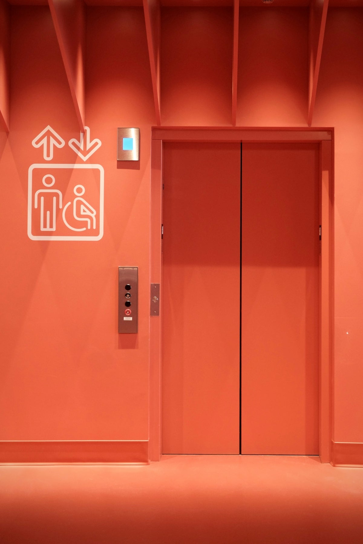 Orange elevator doors with accessibility symbol and buttons